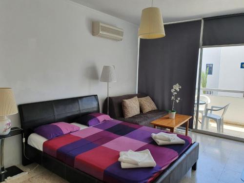 a bedroom with a large bed and a couch at Sea Anemone Apartments in Paphos City