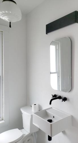 a white bathroom with a sink and a mirror at Shadowcrest in Fleischmanns