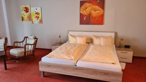 een slaapkamer met een bed en een stoel bij Hotel Haus am Berg in Oberkirch