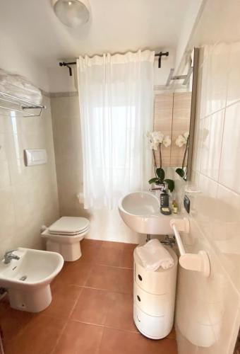 a white bathroom with a sink and a toilet at Appartamenti Sole 1 in Alghero