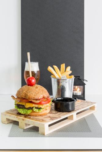 a hamburger and french fries on a table with a drink at Hotel Pax in Split