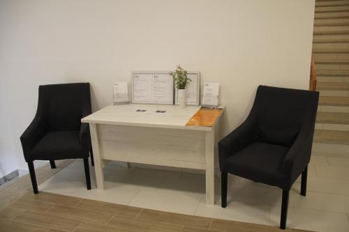 two chairs sitting next to a desk in a room at Harangtorony Szálló in Kőszeg