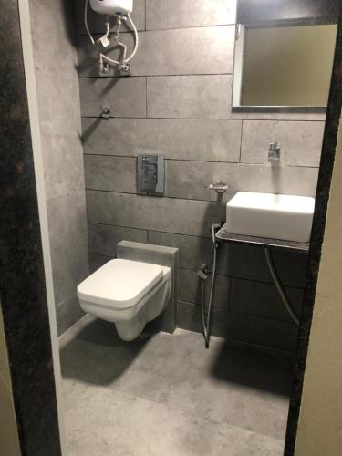 uma casa de banho com um WC, um lavatório e um espelho. em Hotel Rooms Dadar near Station em Mumbai