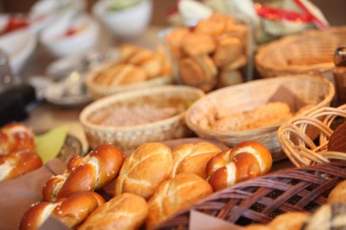 a table topped with baskets filled with different types of bread at Schieners Hotel & Apfelhof Apartments in Wemding