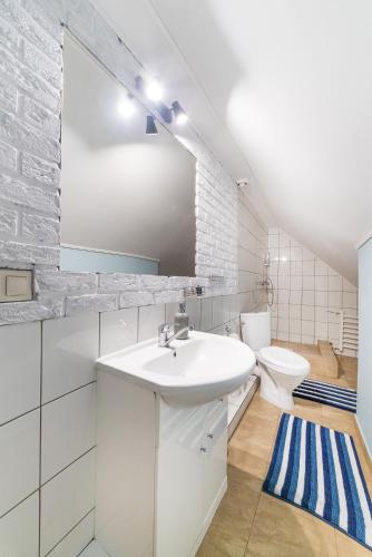 a white bathroom with a sink and a toilet at Apartamenty Mewa in Rewa