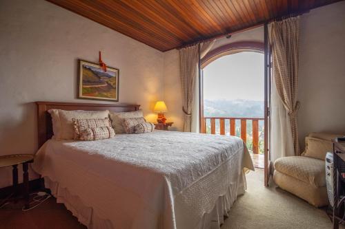 a bedroom with a bed and a large window at Pousada Mansão Edelweiss in Campos do Jordão