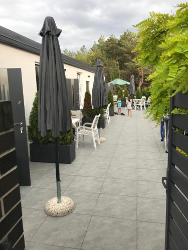 a patio with umbrellas and tables and chairs at Apartamenty i Domki WyDmy Międzywodzie in Międzywodzie