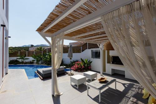 a patio with a pergola and a pool at Chara Sensory Luxury Villa with Heated Pool & Gym, By ThinkVilla in Panormos Rethymno