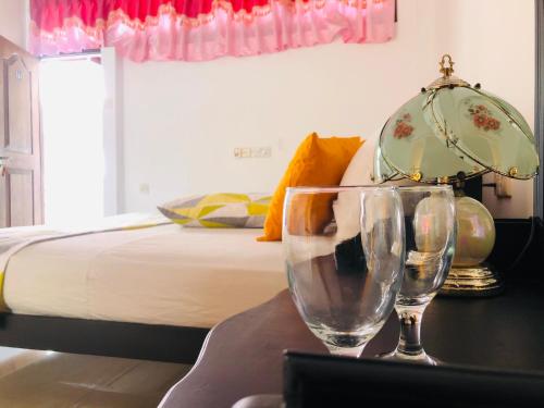 a table with two wine glasses and a bed at Grand Camellia Hotel in Ambalantota