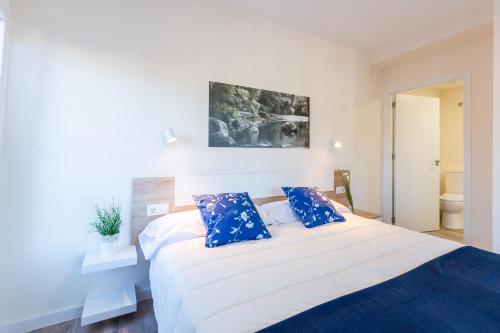a bedroom with a large white bed with blue pillows at MIRADOR DE LA MURALLA in Betanzos