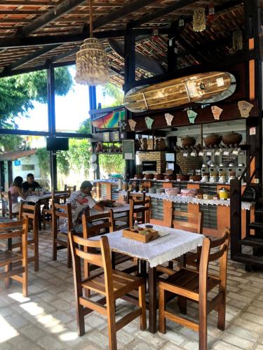 um restaurante com mesas e cadeiras de madeira e pessoas ao fundo em Pousada Casa Do Angelo em Jericoacoara