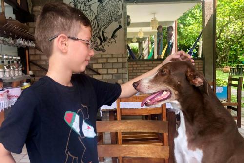 a young boy petting a brown and white dog at Pousada Casa Do Angelo in Jericoacoara
