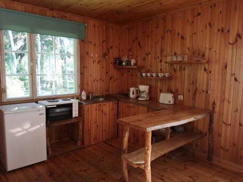 a kitchen with wooden walls and a wooden table at Marta-Lovise puhkemaja Kristiine in Kipi
