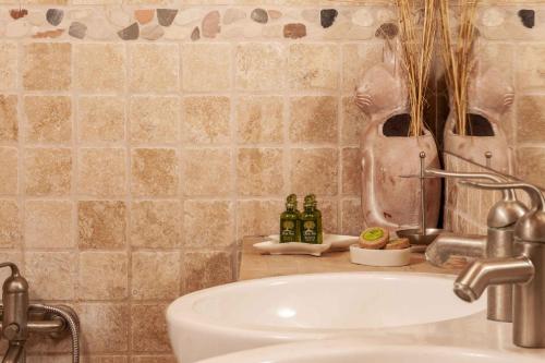 a bathroom with a sink and a counter with bottles at Mounty Island Villas Avra-Calma in Lazaráta
