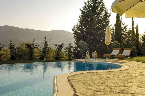 a swimming pool with two chairs and an umbrella at Mounty Island Villas Avra-Calma in Lazaráta