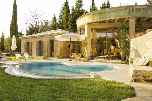 a swimming pool in a yard with an umbrella at Mounty Island Villas Avra-Calma in Lazaráta