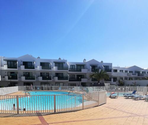 a swimming pool in front of a large building at Marina Beach-Apartamentos Tahiche in Costa Teguise