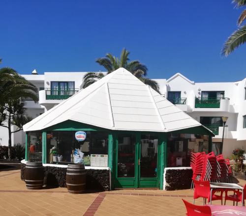 a pavilion with a white umbrella in front of a building at Marina Beach-Apartamentos Tahiche in Costa Teguise