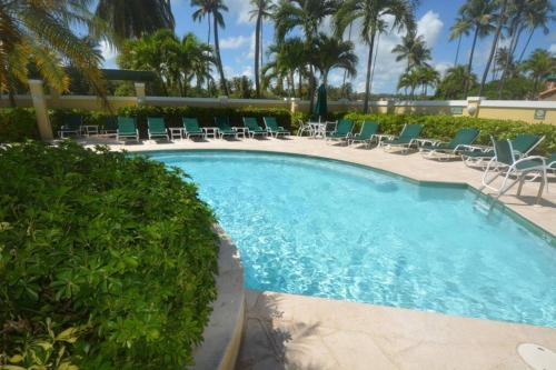 a swimming pool with chairs and palm trees at Beach Villa 215 in Humacao