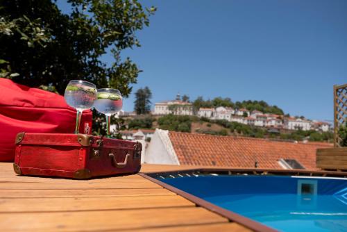 a red suitcase with wine glasses sitting on a table next to a pool at Casa Velha in Alenquer