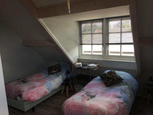 a attic bedroom with two beds and a window at Het Boenhok logies in Lekkerkerk