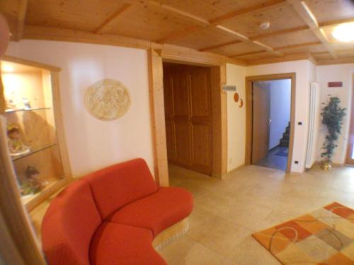 a living room with a red chair and a hallway at Garni Manuela in Cavalese