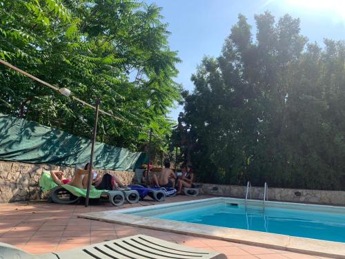 a group of people sitting around a swimming pool at A Due Passi Da in Aci SantʼAntonio