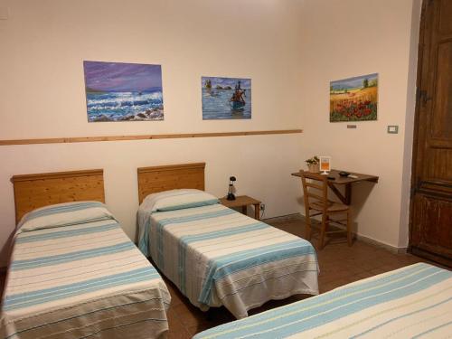 a room with two beds and a table and paintings at A Due Passi Da in Aci SantʼAntonio