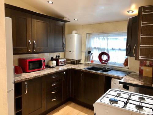 a kitchen with brown cabinets and a red microwave at Beautiful Apartment in Bristol