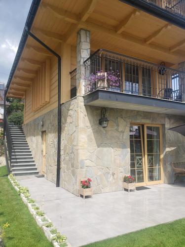 a large stone building with a balcony and stairs at TYLKOWA CHATA in Kościelisko