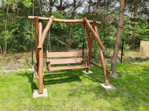 a wooden swing in the grass in a park at Bajka Domek na Roztoczu in Bondyrz