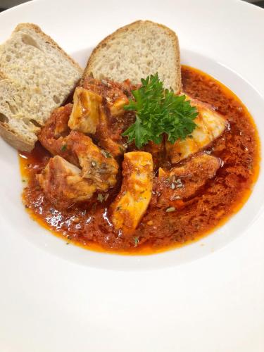 a white plate with a bowl of stew with bread at Hotel Villa Adriana in Monterosso al Mare