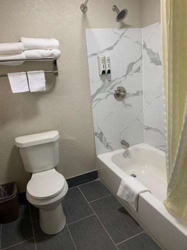 a bathroom with a toilet and a tub and a shower at Crescent Park Motel & Suites in Littlefield