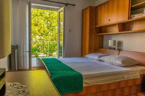 a bedroom with a bed with a green blanket and a window at Apartments White & Green in Malinska in Malinska