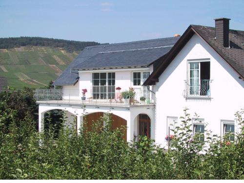 a white house with a balcony with flowers on it at Weingut Fries in Maring-Noviand