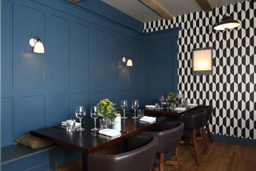 a dining room with blue walls and black tables and chairs at The Crown And Thistle, Abingdon in Abingdon