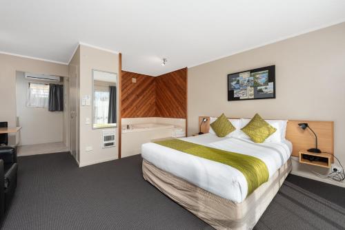 Habitación de hotel con cama grande y bañera en ASURE Macy's Motor Inn, en Tauranga