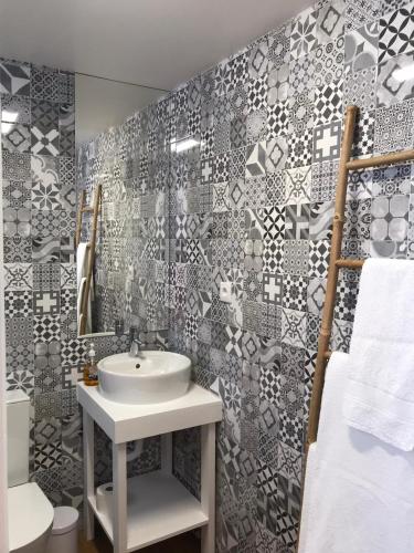 a bathroom with a white sink and a tile wall at Estúdio Azul in Ponta Delgada