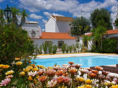 a pool in front of a house with flowers at Casas de Santa Rita in Évora Monte