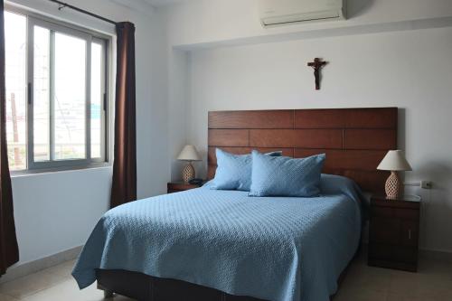 a bedroom with a bed with a blue comforter and a window at Suites Caribe in Boca del Río