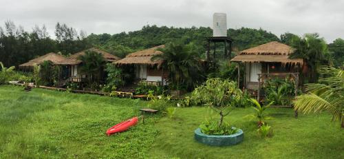 a group of huts with a red boat in the grass at Moon Nest in Dhoāpālong