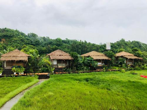 a group of huts in a field with grass at Moon Nest in Dhoāpālong