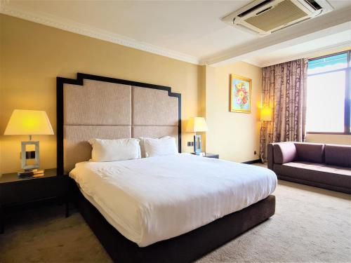 a bedroom with a large bed and a couch at Merdeka Hotel Kluang in Kluang