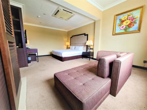 Merdeka Hotel Kluang في كلوانج: غرفه فندقيه بسرير واريكه