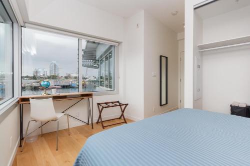 a bedroom with a bed and a desk and a window at Historic Waterside With Spectacular Johnson Bridge Views in Victoria