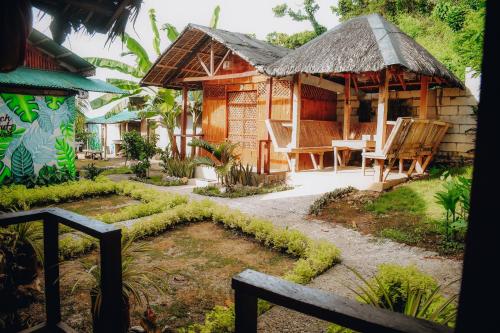 a house with a table and chairs in a garden at Suba Beach Nipa Huts in Daanbantayan