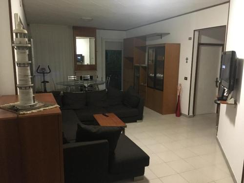 ein Wohnzimmer mit einem schwarzen Sofa und einer Küche in der Unterkunft CASA DE NELLA in Porto San Giorgio