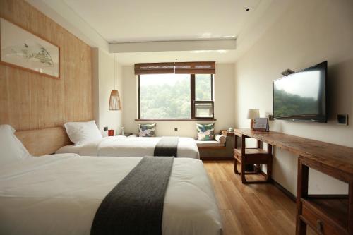 a hotel room with two beds and a flat screen tv at 武当山太和紫隐酒店 in Wudangshan