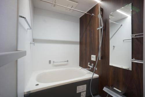 a bathroom with a white tub and a mirror at WIRES HOTEL James zaka in Tokyo