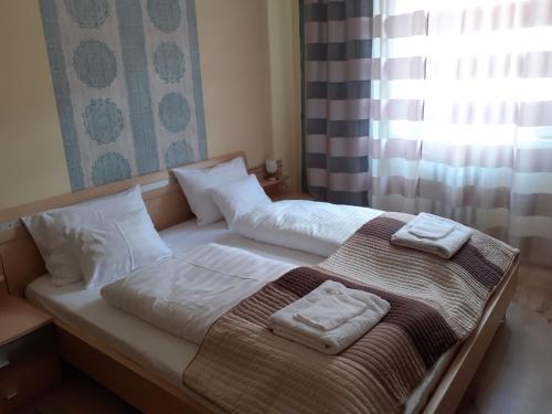 Una cama con dos toallas encima. en Macskafogo, tunderi szallas a belvarosban en Győr